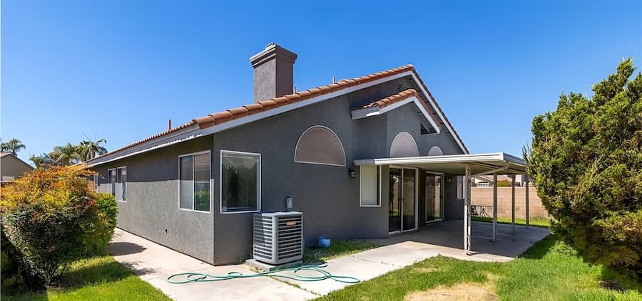A beautifully renovated bluish gray house with a manicured green lawn, showcasing a completed Southern California property transformation.
