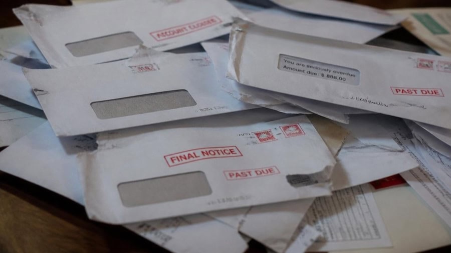 Pile of unopened mail and envelopes stacked on a table
