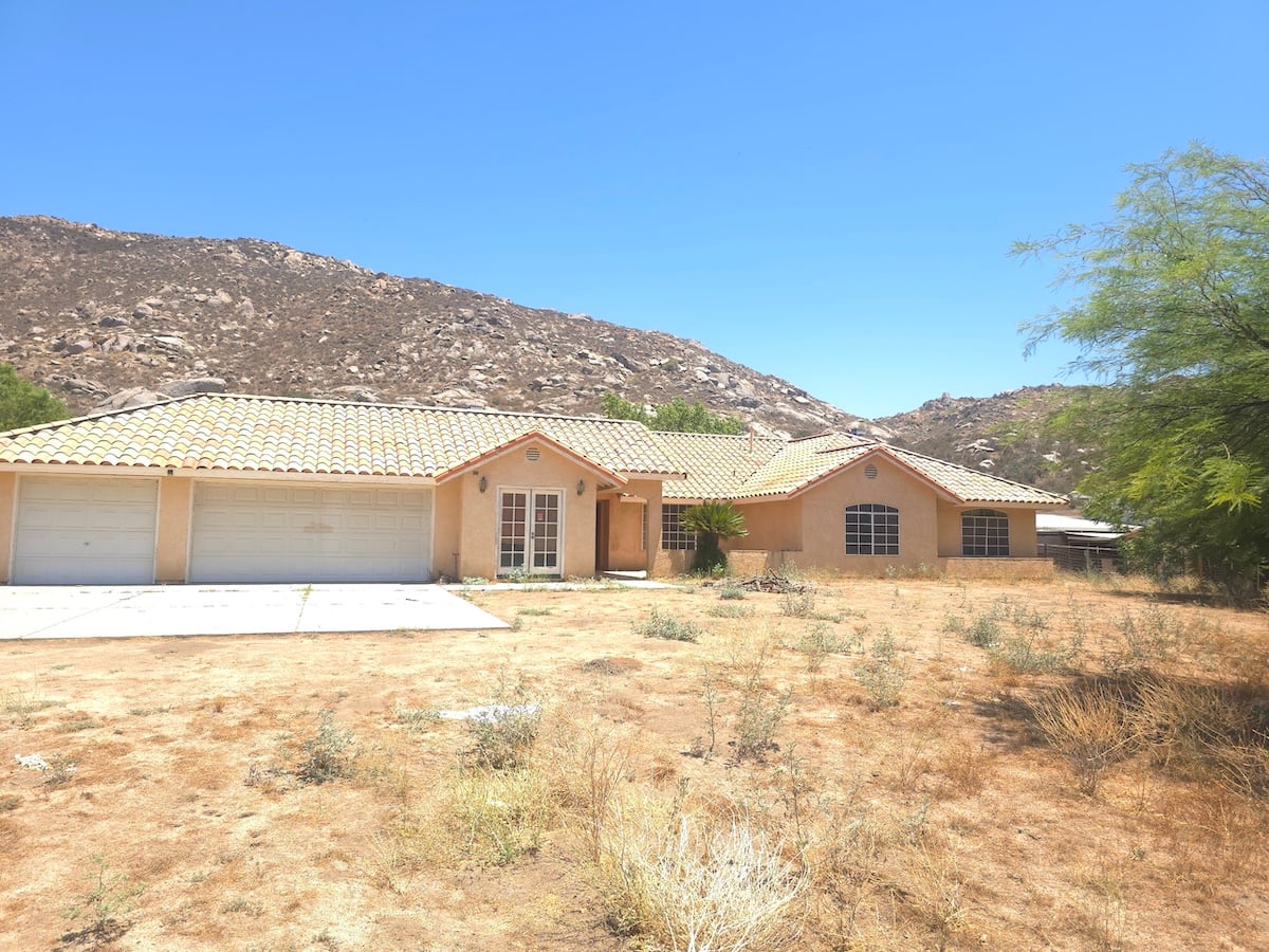 Single-story house on Firecat Rd in Hemet with dirt in front yard full of dry weeds before the as-is sale