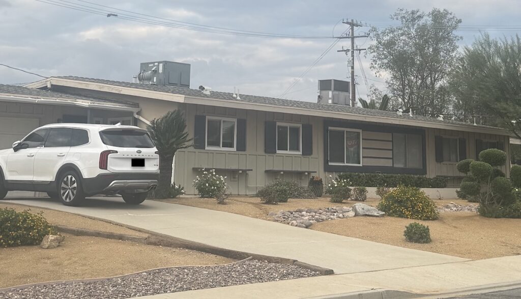 Single-story Sun City home in Menifee with board-and-batten siding, a rooftop AC unit, and desert landscaping after the as-is sale